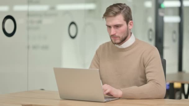 Kreativní mladý muž s notebookem s bolestí v krku v kanceláři — Stock video