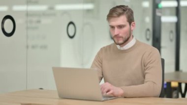 Dizüstü bilgisayarlı yaratıcı genç adam Kameraya gülümsüyor 