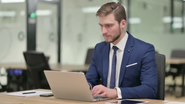 Geschäftsmann schaut mit Laptop im Büro auf Kamera — Stockvideo