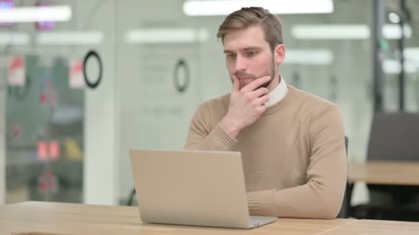 Jeune homme créatif avec ordinateur portable, penser au bureau — Video