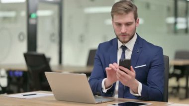 İş yerinde Smartphone kullanan Laptop sahibi bir iş adamı