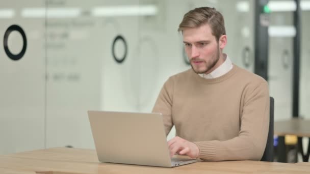 Jeune homme créatif ayant une perte sur ordinateur portable au bureau — Video
