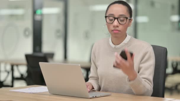 Kreativ afrikansk kvinna med bärbar dator talar på telefon — Stockvideo