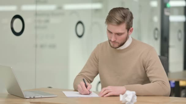 Kreativer junger Mann versäumt es, auf Papier zu schreiben — Stockvideo