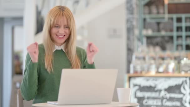Успешная молодая женщина празднует на ноутбуке в кафе — стоковое видео