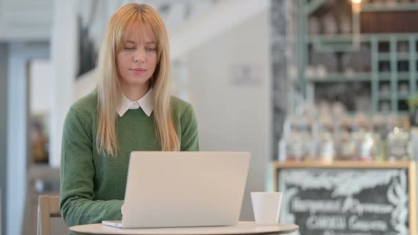 カフェでノートパソコンをタイプしながら手首の痛みを持つ若い女性 — ストック動画