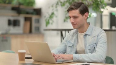 Dizüstü bilgisayarlı Yaratıcı Genç Adam Başparmağını kaldırdı 