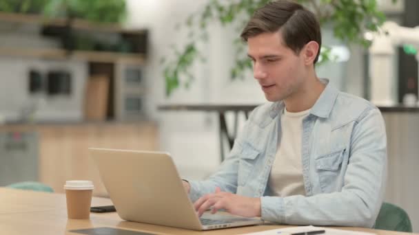 Pomyślny twórczy młody człowiek świętuje na laptopie w pracy — Wideo stockowe