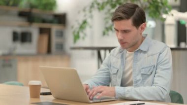 Dizüstü bilgisayarı olan yaratıcı genç adam sırt ağrısı çekiyor. 