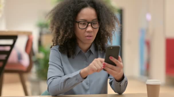 Ung afrikansk kvinne som bruker smarttelefon på jobben – stockvideo