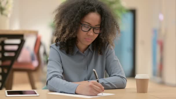 勤勉な若いアフリカの女性と紙に書く — ストック動画