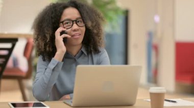 Dizüstü bilgisayarlı Genç Afrikalı Kadın Akıllı Telefonla Konuşuyor 