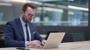 Laptop öksüren orta yaşlı iş adamı. 