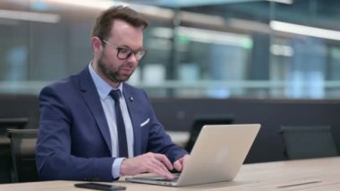 Bilgisayarlı orta yaşlı iş adamı kamerayı işaret ediyor.