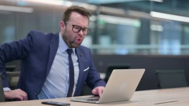 Bilgisayarı olan orta yaşlı iş adamı sırt ağrısı çekiyor. 