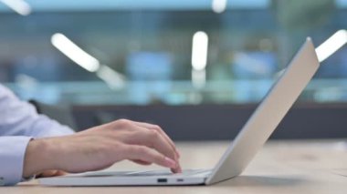 Dizüstü bilgisayarda yazan genç adamın ellerini kapat. 