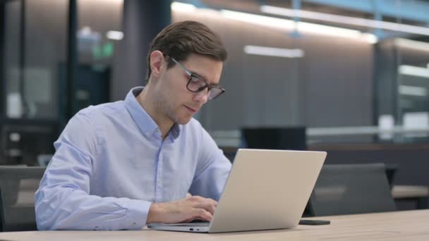 Młody człowiek z Laptop myślenia w pracy — Wideo stockowe