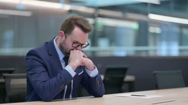 Середнього віку бізнесмен побоюється сидячи в офісі — стокове відео