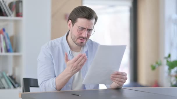 Muž v brýlích reaguje na ztrátu při čtení dokumentů — Stock video
