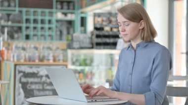 Bilgisayarda çalışırken Kameraya Gülümseyen Genç Kadın