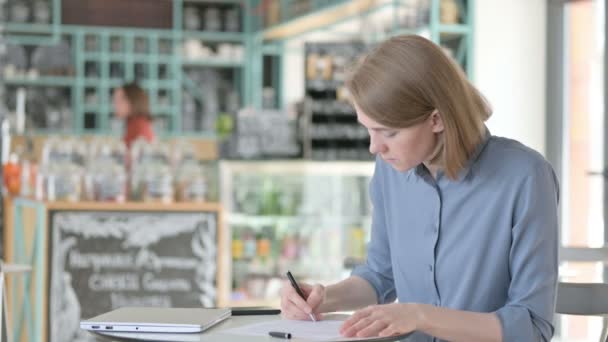 Молода жінка читає документи в кафе — стокове відео