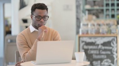 Cafe 'de dizüstü bilgisayar kullanırken yaratıcı Afrikalı Adam Düşünüyor 