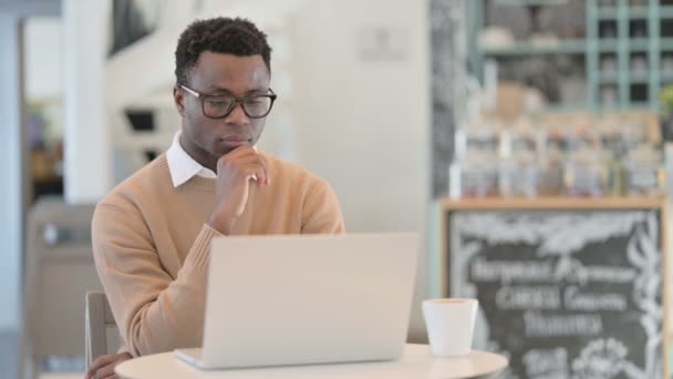 Creatieve Afrikaanse Man denken tijdens het gebruik van Laptop in Cafe — Stockvideo