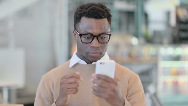 Hombre africano creativo que tiene pérdida mientras usa Smartphone — Vídeos de Stock