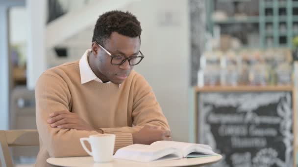 African American Man Reading Book Ενώ πίνοντας καφέ στο καφέ — Αρχείο Βίντεο