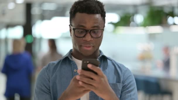 Retrato de un joven africano celebrando en Smartphone — Vídeos de Stock