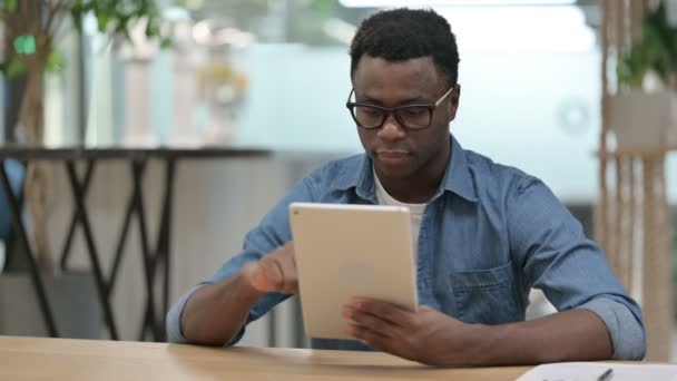 Aantrekkelijke jonge Afrikaanse man met behulp van Tablet in Modern Office — Stockvideo