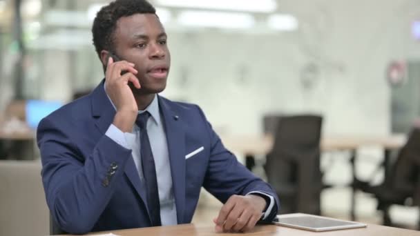Uomo d'affari africano che parla su smartphone in ufficio moderno — Video Stock
