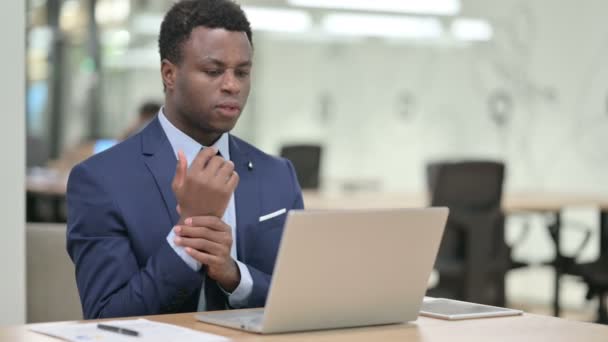 Afrikai üzletember, akinek csuklófájdalma van, miközben a Laptopon dolgozik — Stock videók