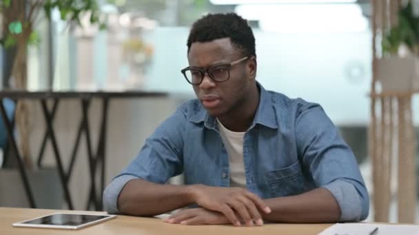Homem Africano Jovem Perturbado Enquanto Sentado no Escritório Moderno — Vídeo de Stock