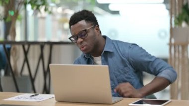 Genç Afrikalı Adam dizüstü bilgisayar kullanırken sırt ağrısı çekiyor 