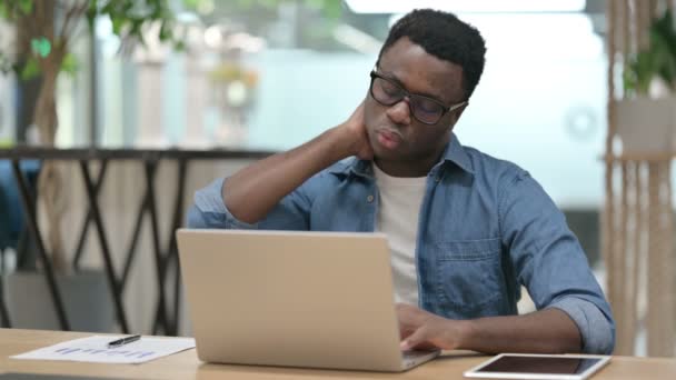 Giovane uomo africano che ha dolore al collo mentre digita sul computer portatile — Video Stock