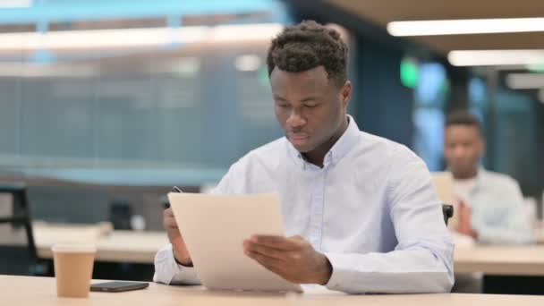 Un om de afaceri african citește documente în birou — Videoclip de stoc