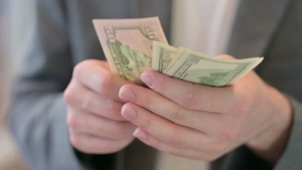 Nahaufnahme der Hände eines jungen Mannes, der Dollars zählt — Stockvideo