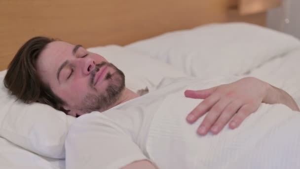 Casual jonge man wakker uit slapen in bed — Stockvideo