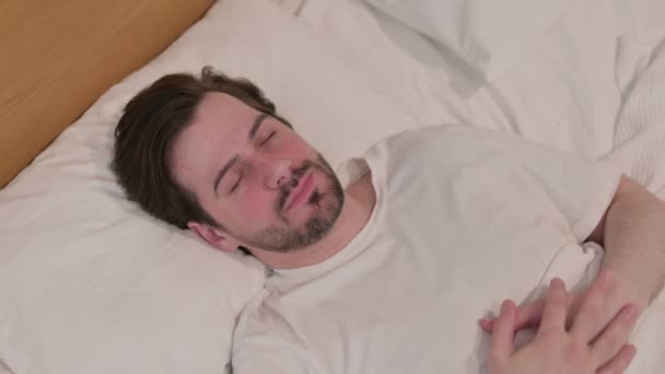 Casual giovane uomo svegliarsi dal sonno a letto — Video Stock