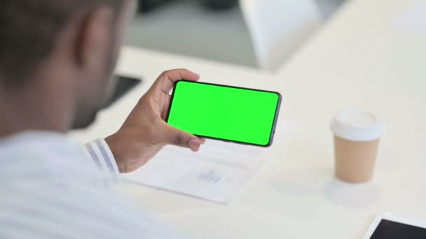 Вид сзади на Африканского человека с помощью смартфона с зеленым хроматическим экраном — стоковое видео
