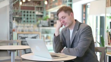 Laptop 'u olan genç adam kafede kestiriyor. 