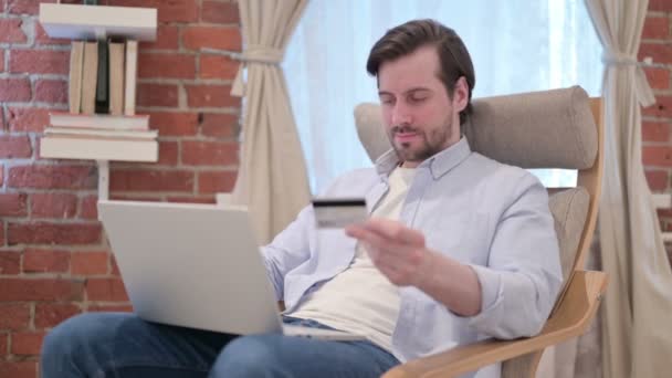Lässiger junger Mann bezahlt online am Laptop auf dem Sofa — Stockvideo