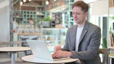 Dizüstü bilgisayarı olan genç adam boyun ağrısı çekiyor. 