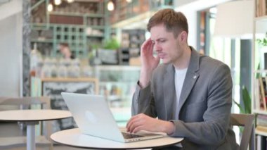 Dizüstü bilgisayarı olan genç adam baş ağrısı çekiyor. 