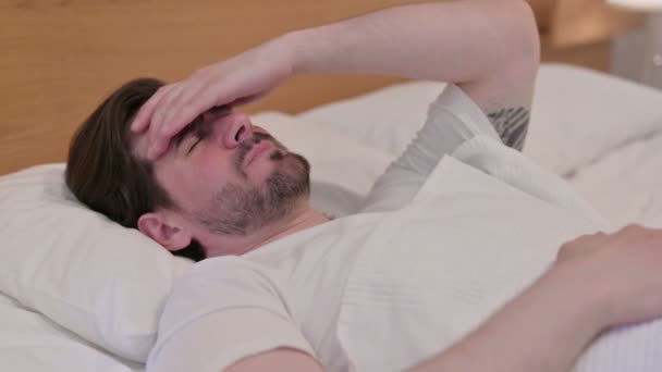 ベッドで寝ている間に頭痛を持っているカジュアル若い男 — ストック動画