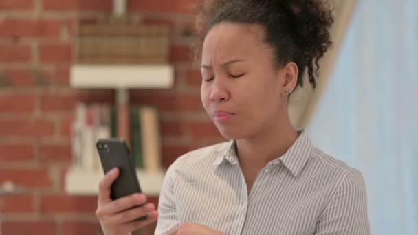 Retrato de una mujer afroamericana reaccionando a la pérdida en un teléfono inteligente — Vídeo de stock