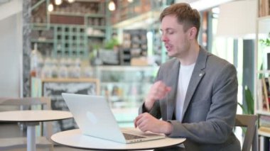 Laptoplu genç adam öksürüyor. 