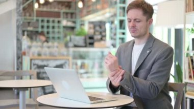 Dizüstü bilgisayarı olan genç adam bilek ağrısı çekiyor. 