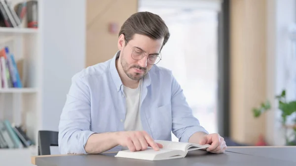 Людина в окулярах читання книга в офісі — стокове фото